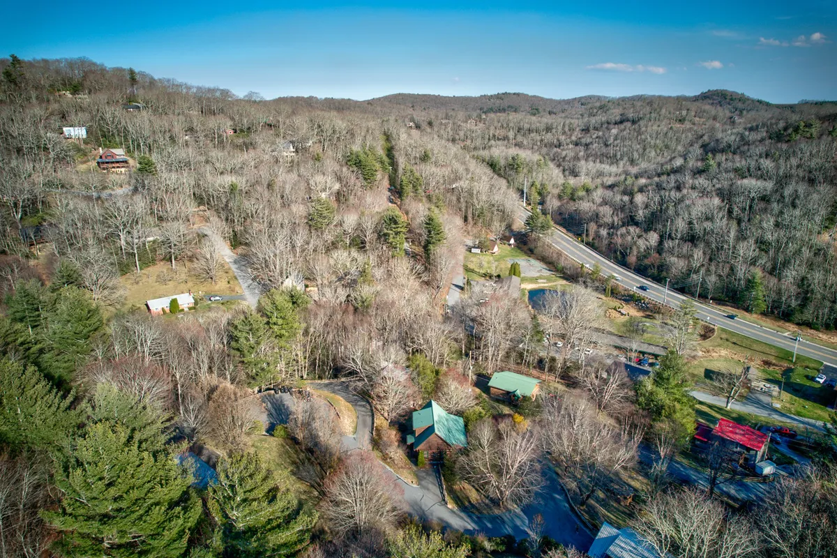 A scenic, wide-angle view of rolling tree-covered hills dotted with houses and winding roads, suggesting easy access to nature and local exploration. The peaceful landscape is ideal for hiking, biking, and outdoor discovery, tying into the theme of family adventures in the surrounding area.